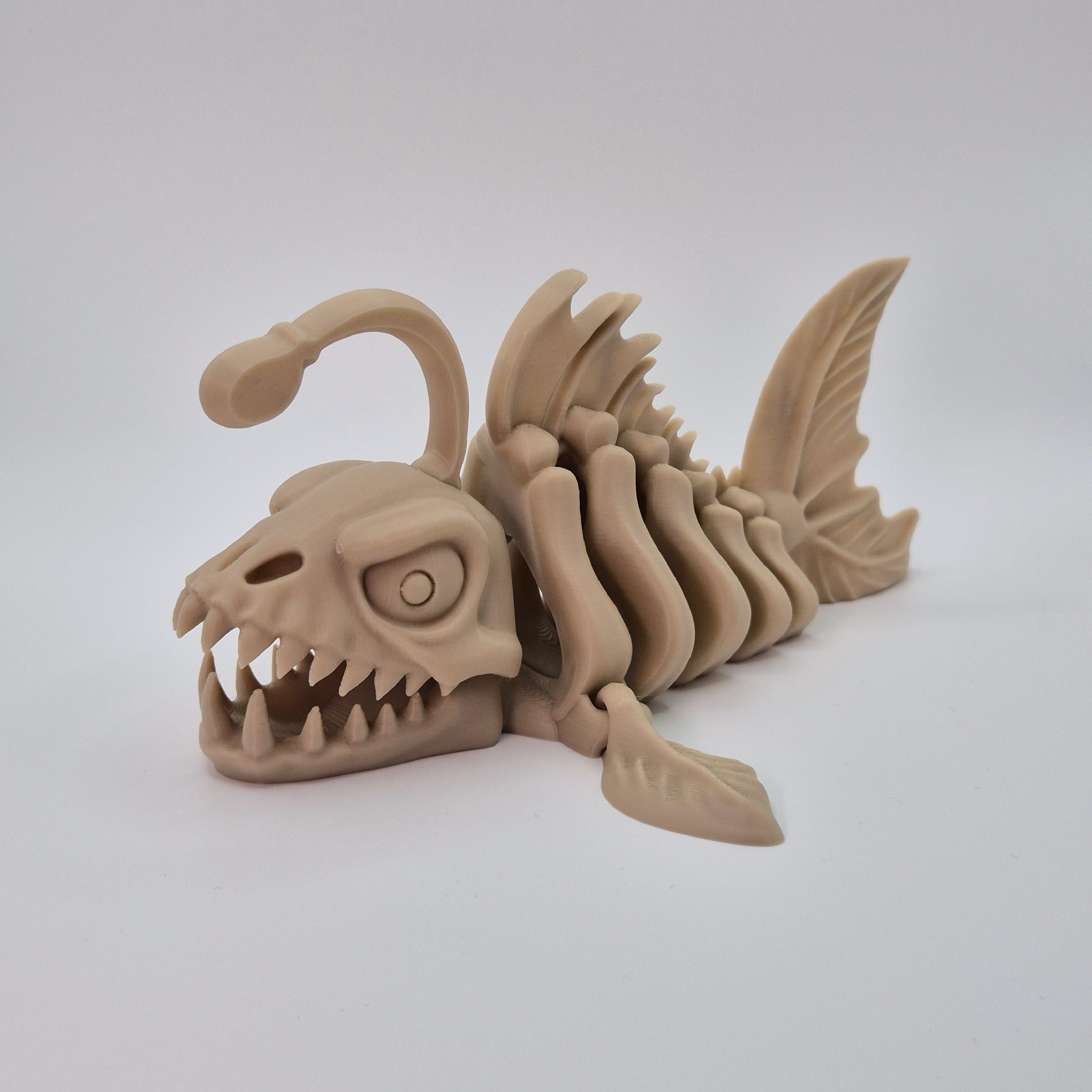 Angled front view of a bone-coloured 3D-printed articulating skeleton Anglerfish toy