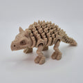 Angled front view of a bone-coloured 3D-printed articulating skeleton Ankylosaurus toy