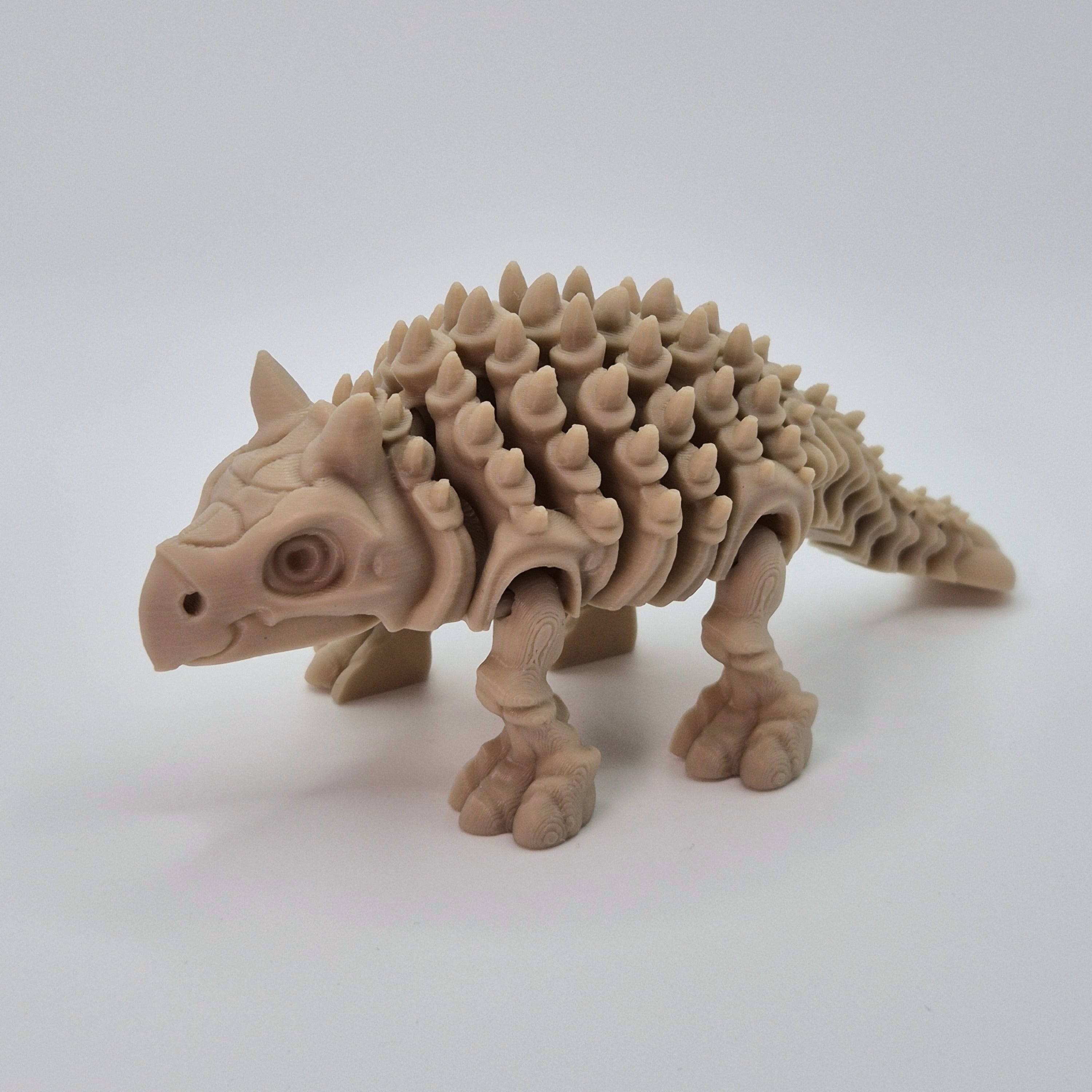 Angled front view of a bone-coloured 3D-printed articulating skeleton Ankylosaurus toy