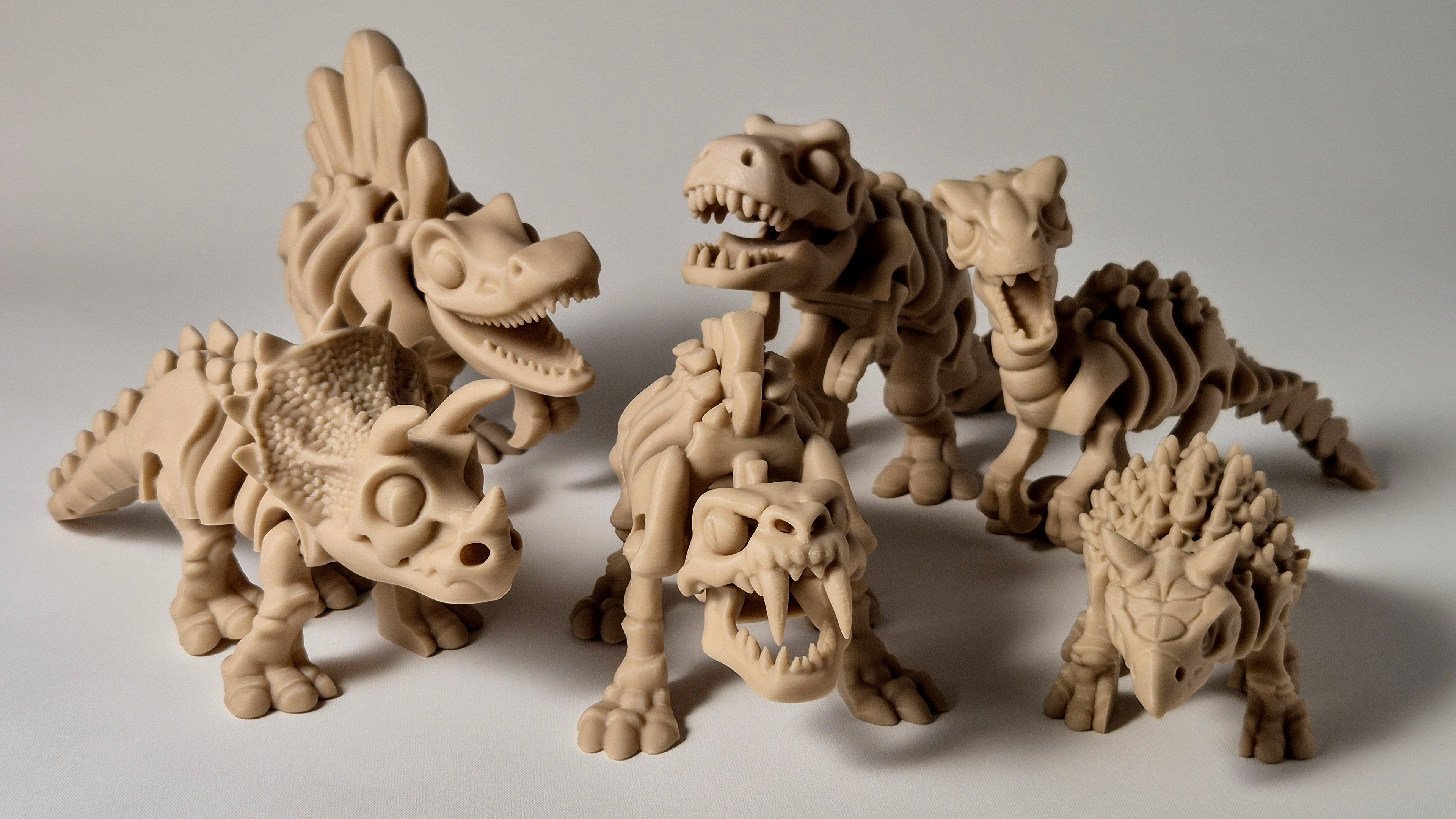 Bone coloured 3D printed articulating prehistoric dinosaur toy range displayed together
