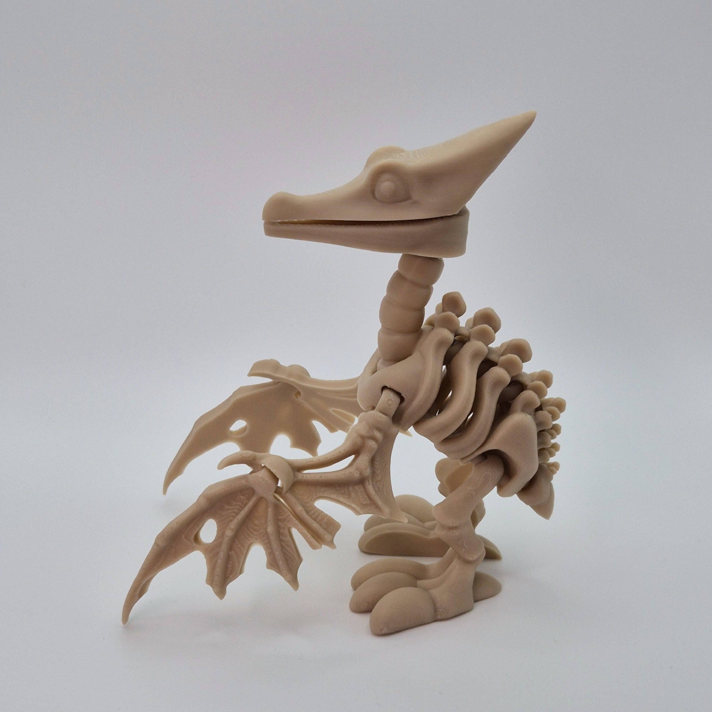 Side view of a bone-coloured 3D-printed articulating skeleton Pteranodon toy
