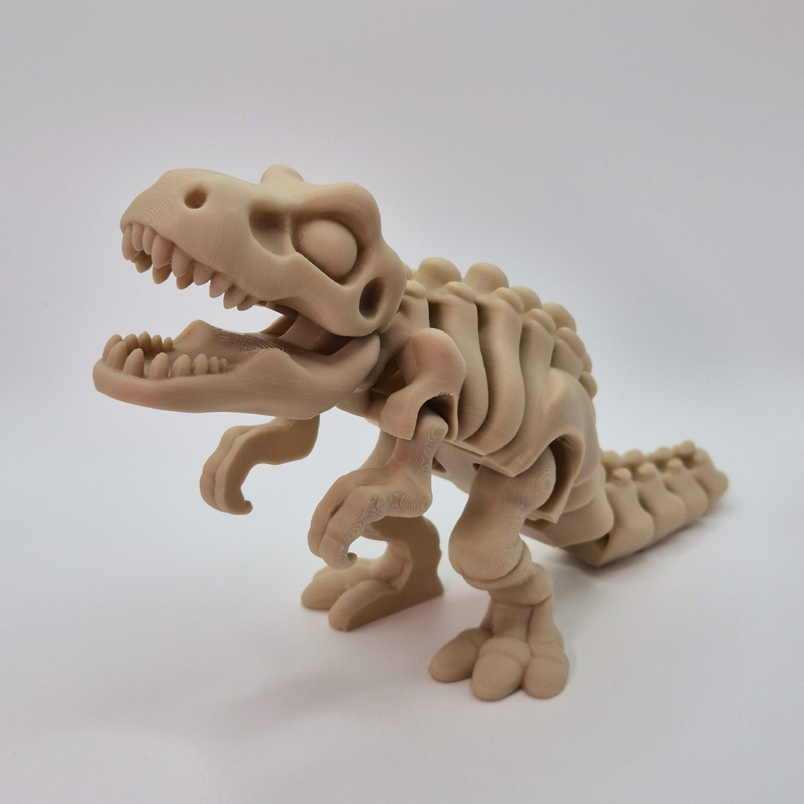 Angled front view of a bone-coloured 3D-printed articulating skeleton Tyrannosaurus Rex toy