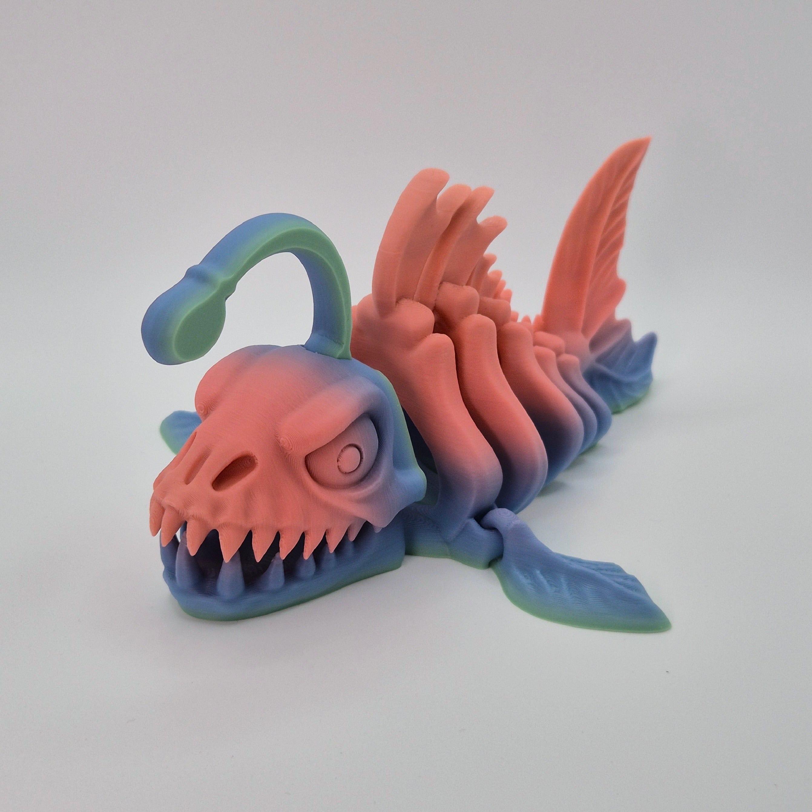 Angled front view of a sherbet-coloured 3D-printed articulating skeleton Anglerfish toy