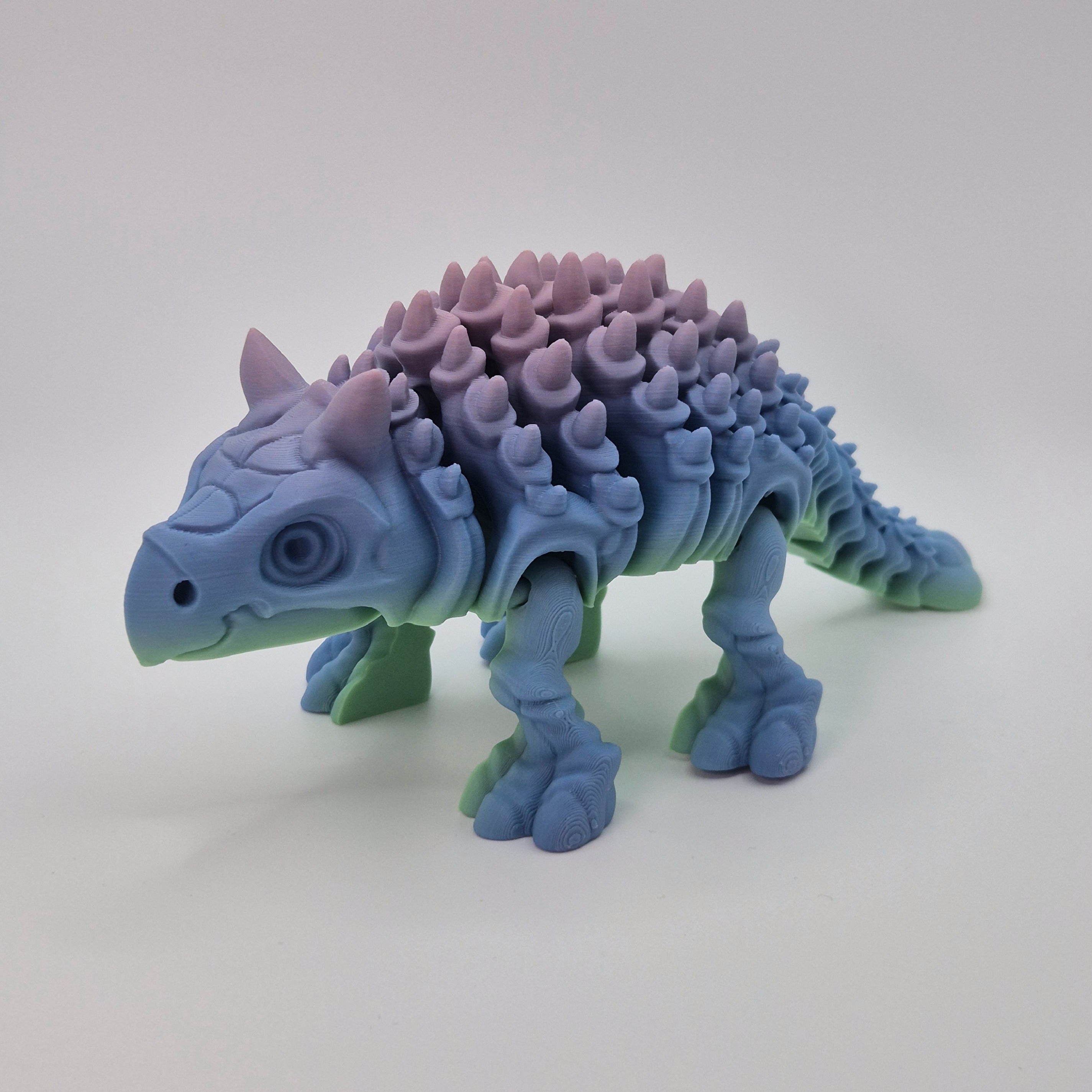 Angled front view of a sherbet-coloured 3D-printed articulating skeleton Ankylosaurus toy