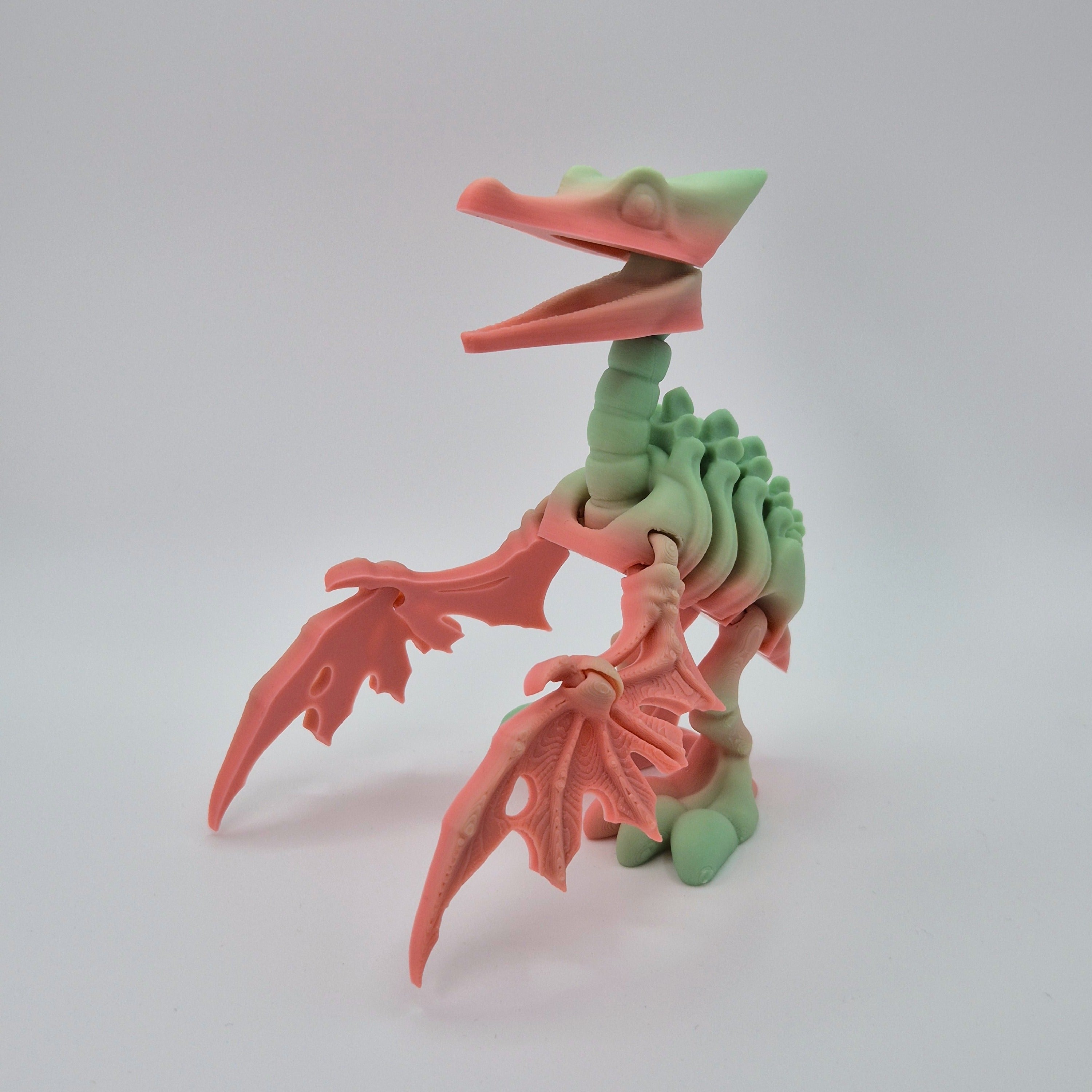 Angled front view of a sherbet-coloured 3D-printed articulating skeleton Pteranodon toy