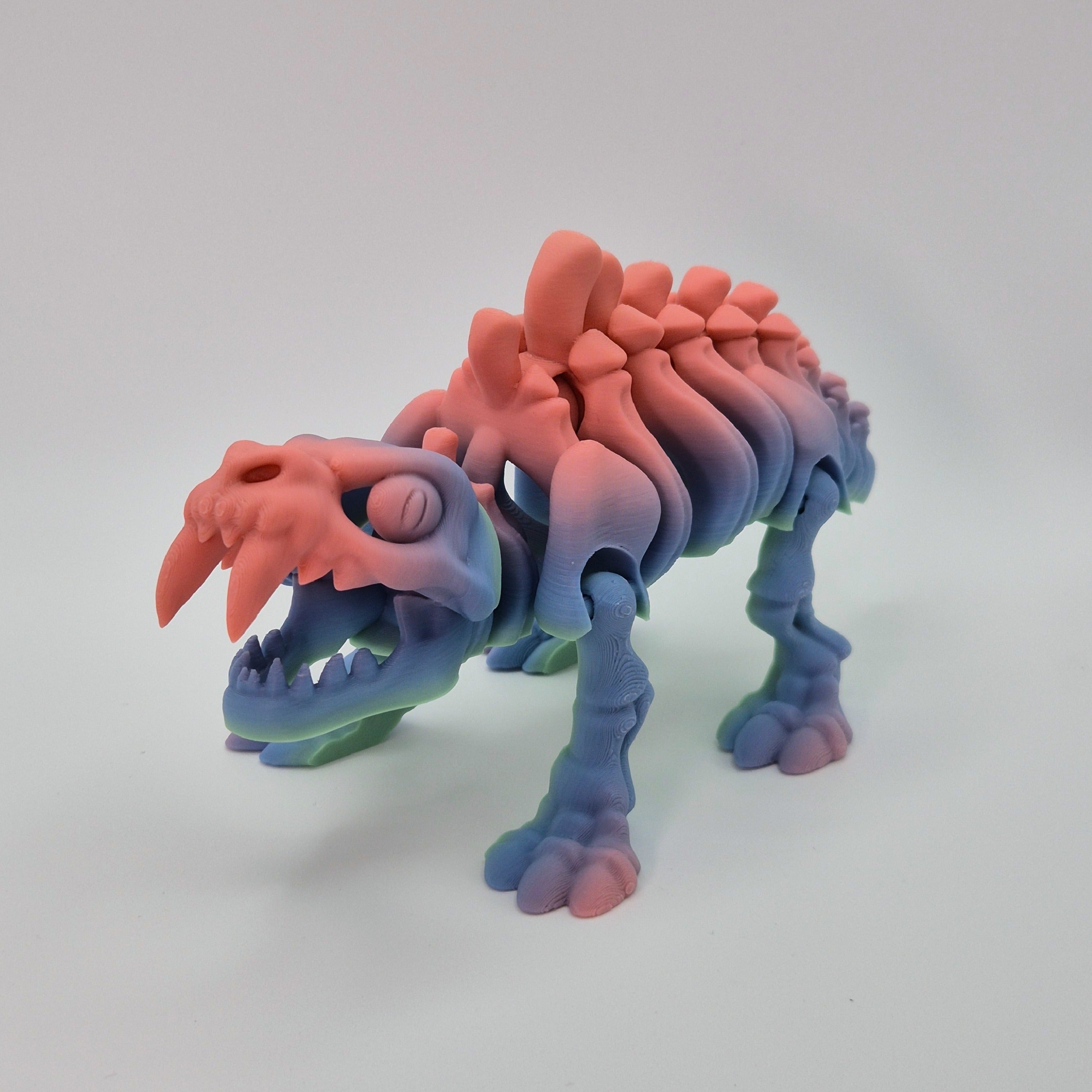 Angled front view of a sherbet-coloured 3D-printed articulating skeleton Sabre-toothed Tiger toy